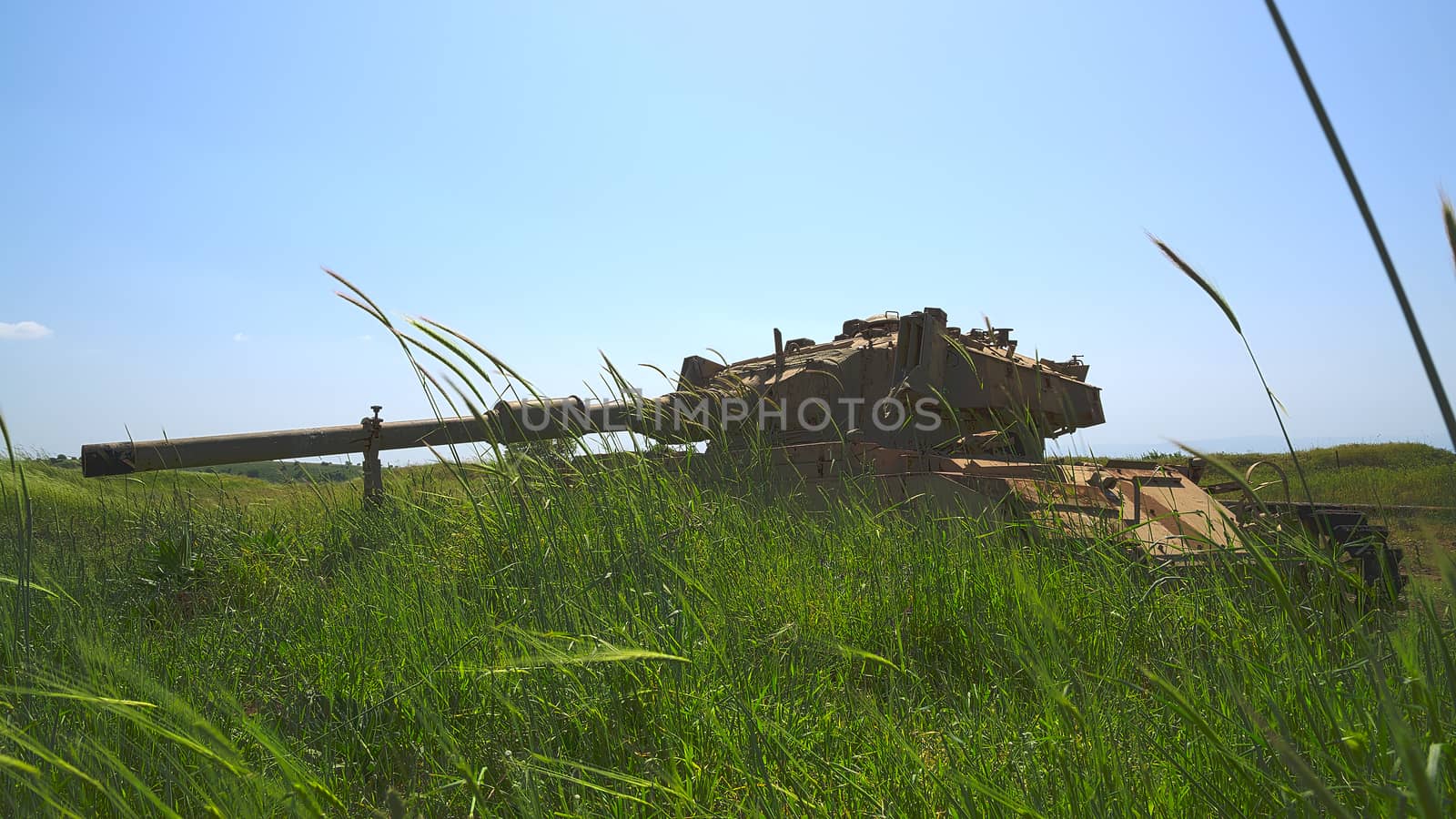 Old Israeli tank in the tall grass against blue sky. HDR photo.