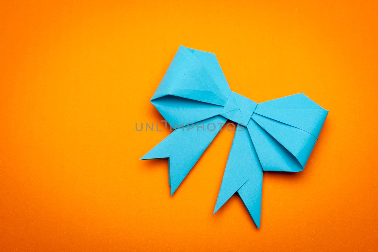 blue origami paper bow on orange paper background