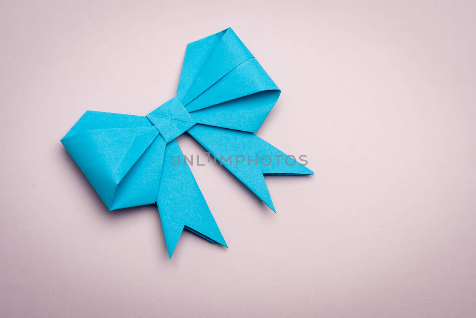 blue origami paper bow on orchid paper background
