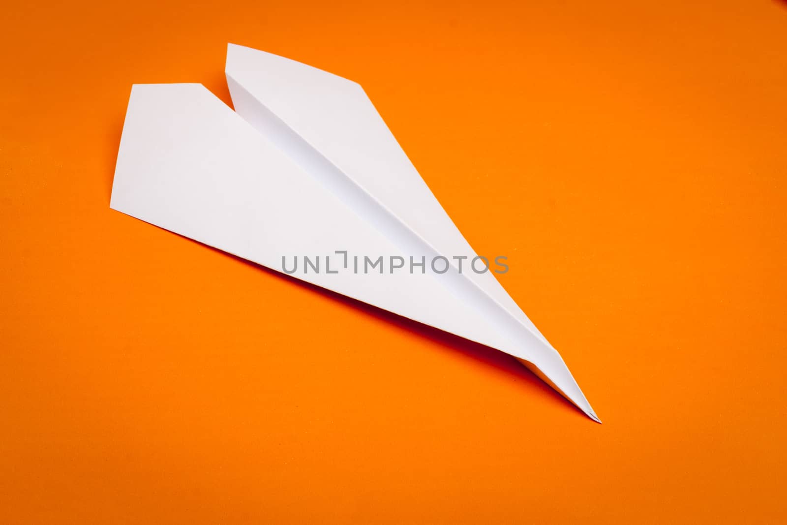white paper plane on orage paper background
