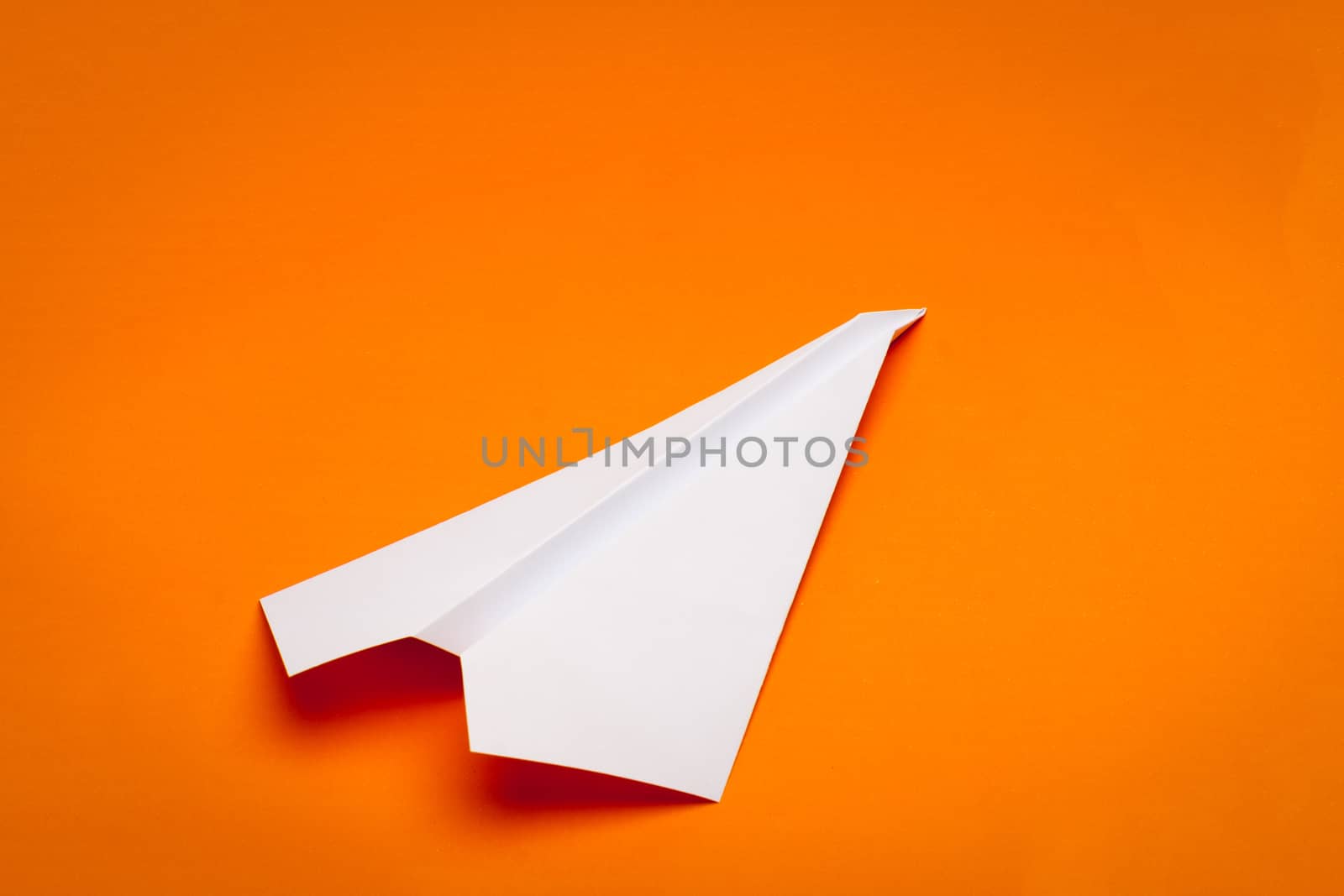 white paper plane on orage paper background