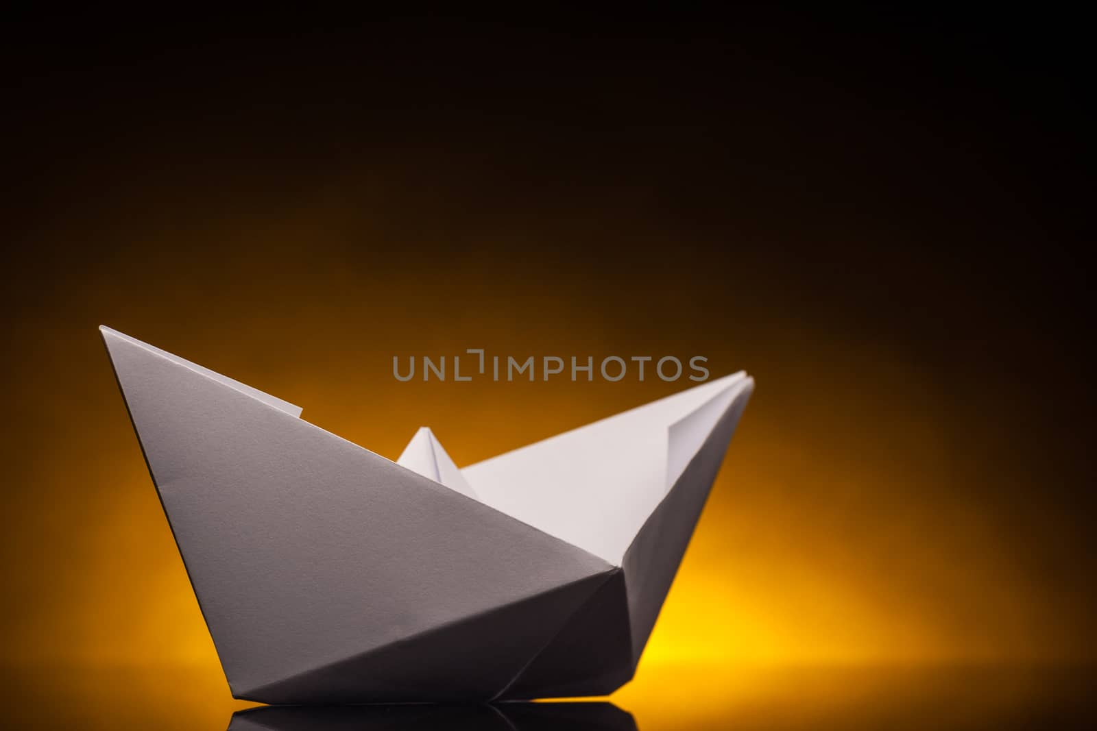 white origami paper boat with orange back light