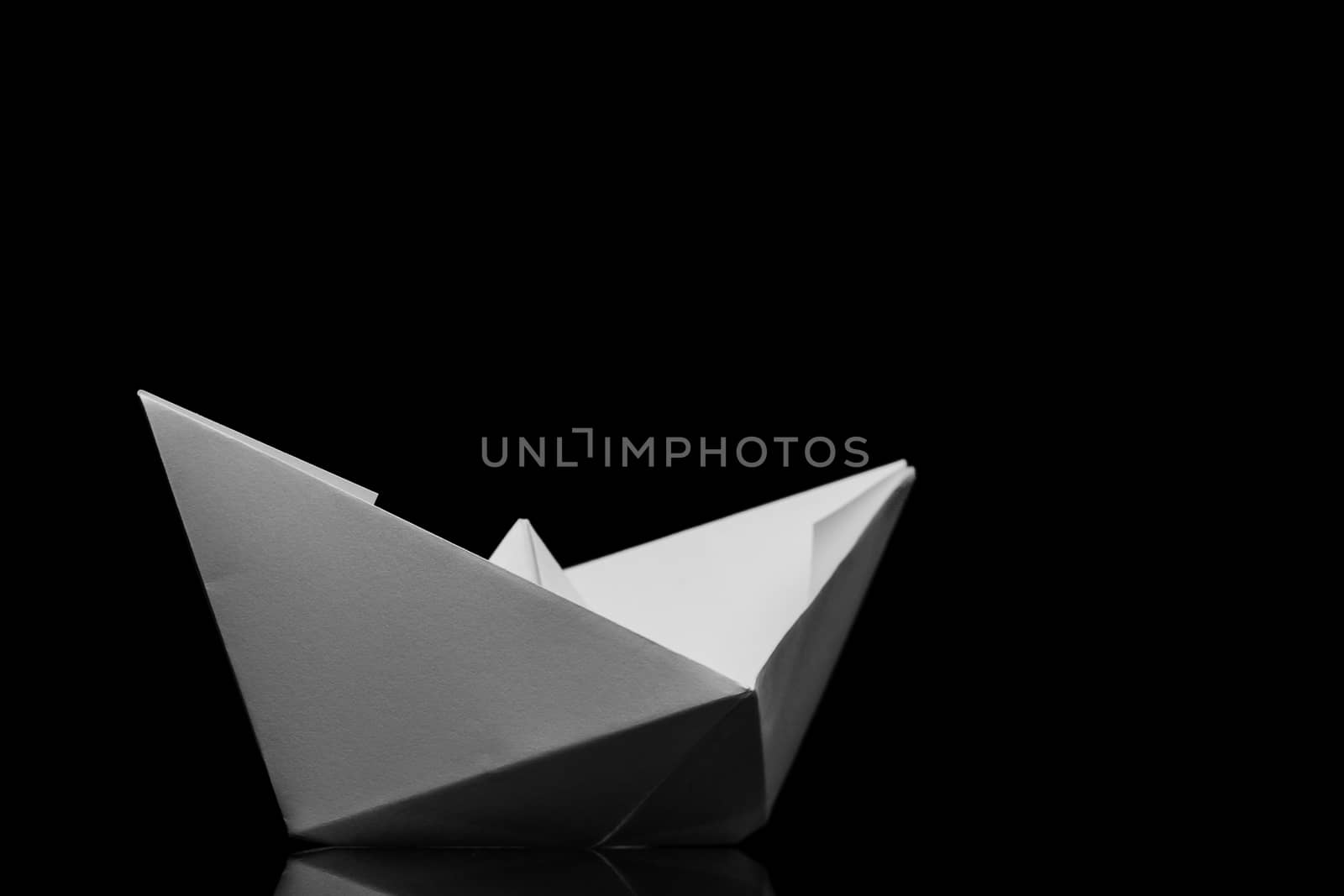 white origami paper boat on black background