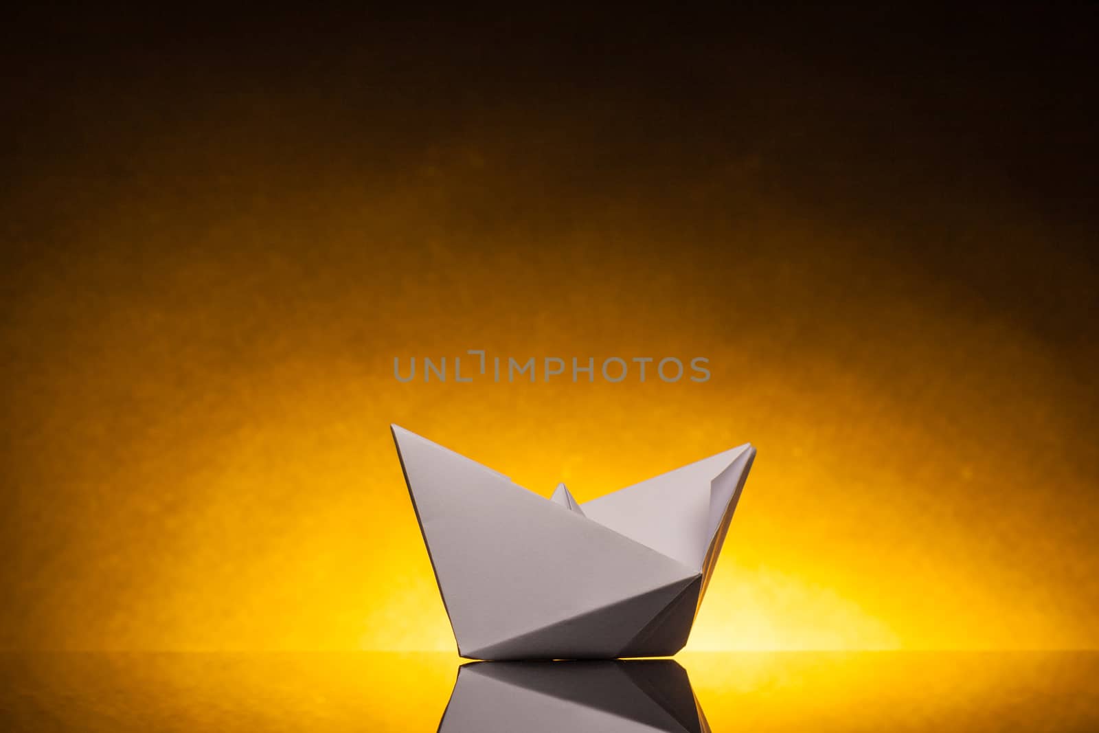 white origami paper boat with orange back light