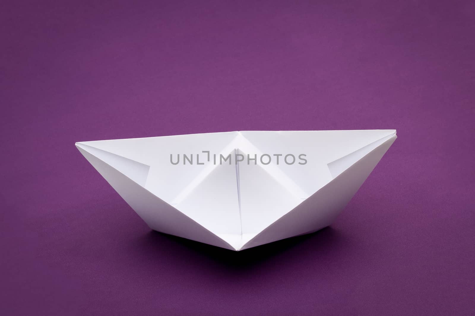 white paper boat on purple paper background