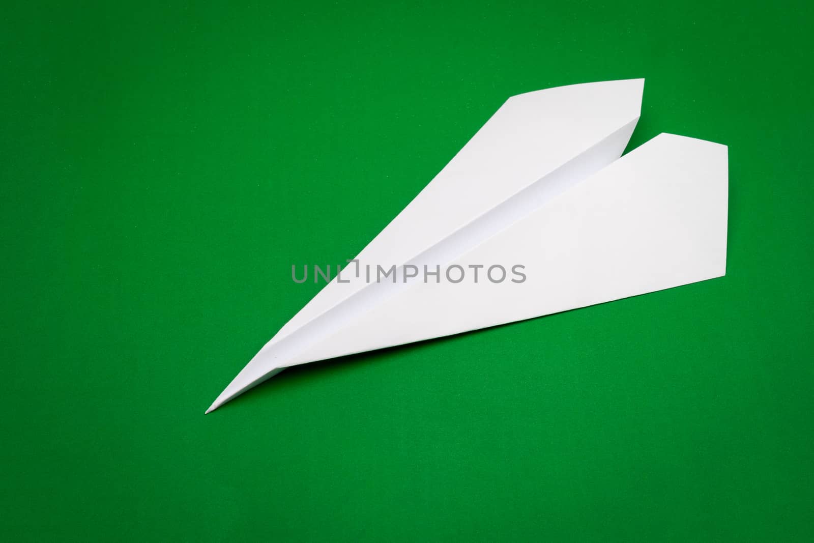 white paper plane on green paper background