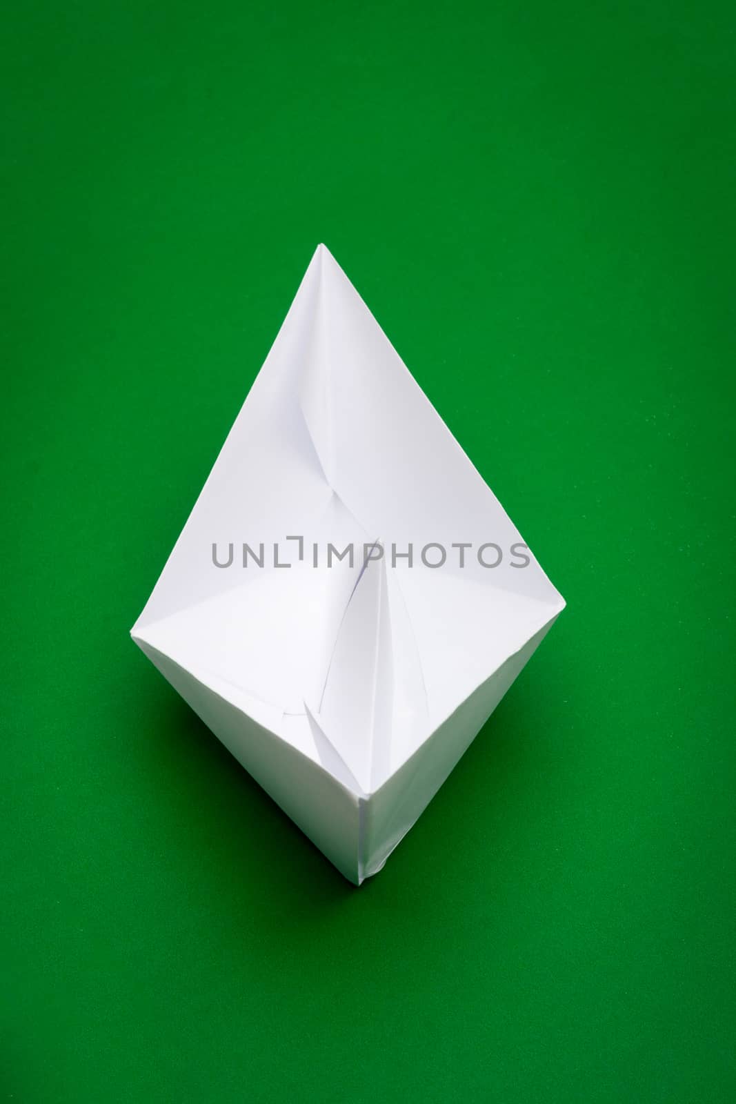 white paper boat on green paper background