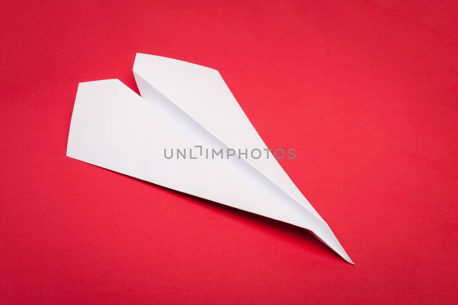 white paper plane on red paper background