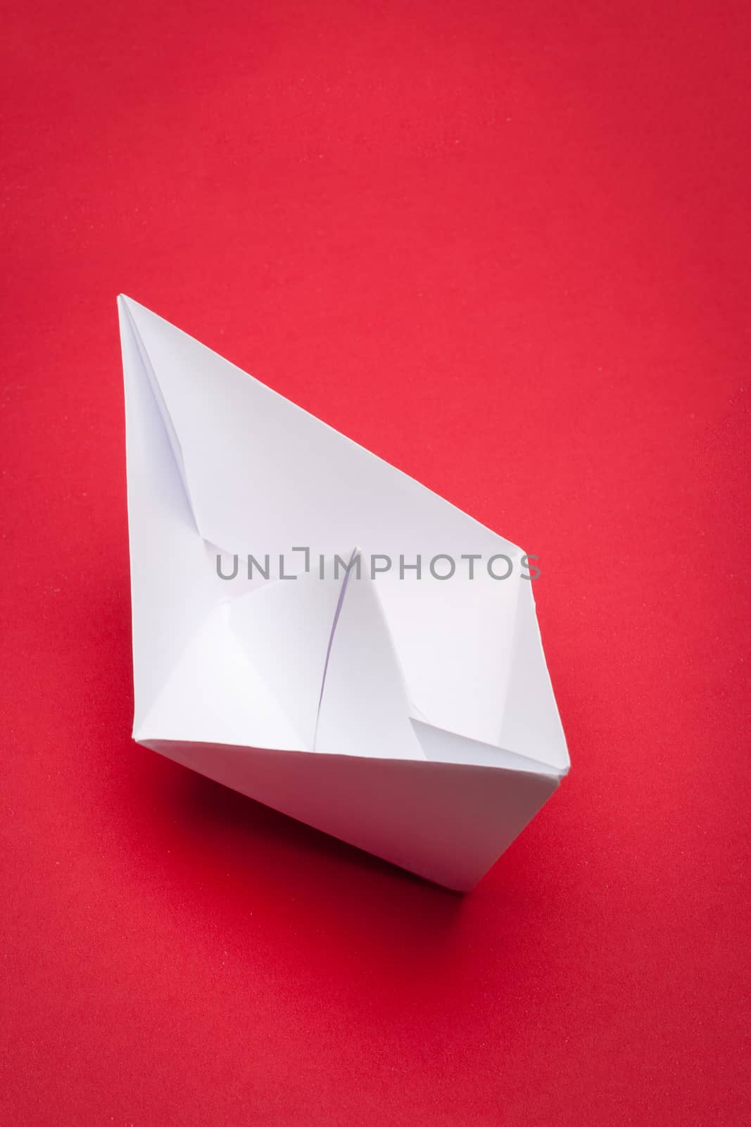 white paper boat on red paper background