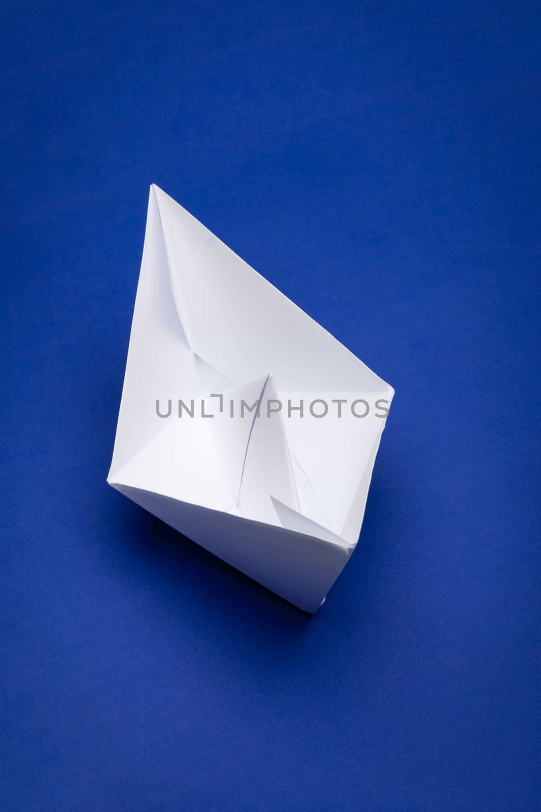 white paper boat on blue paper background