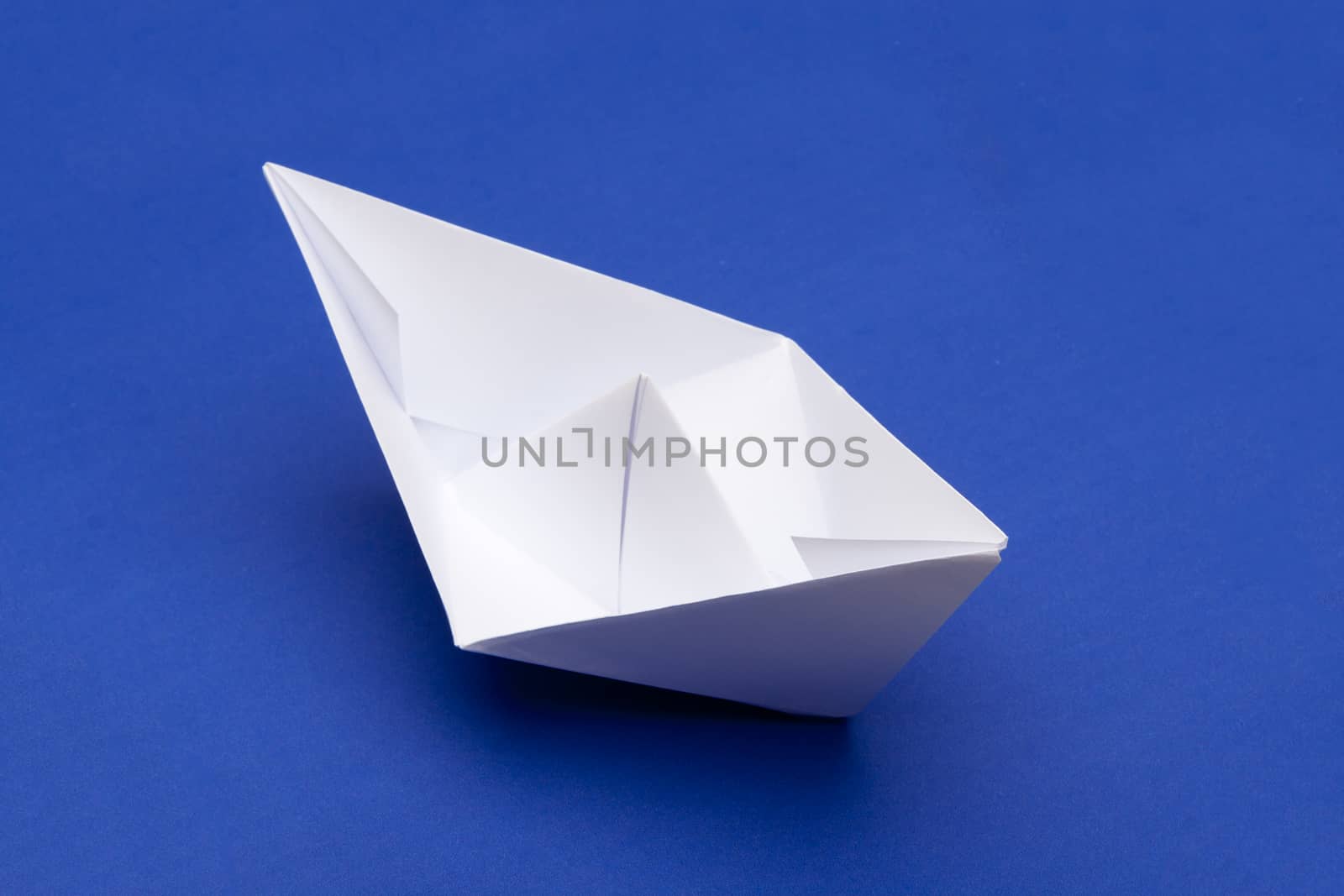 white paper boat on blue paper background