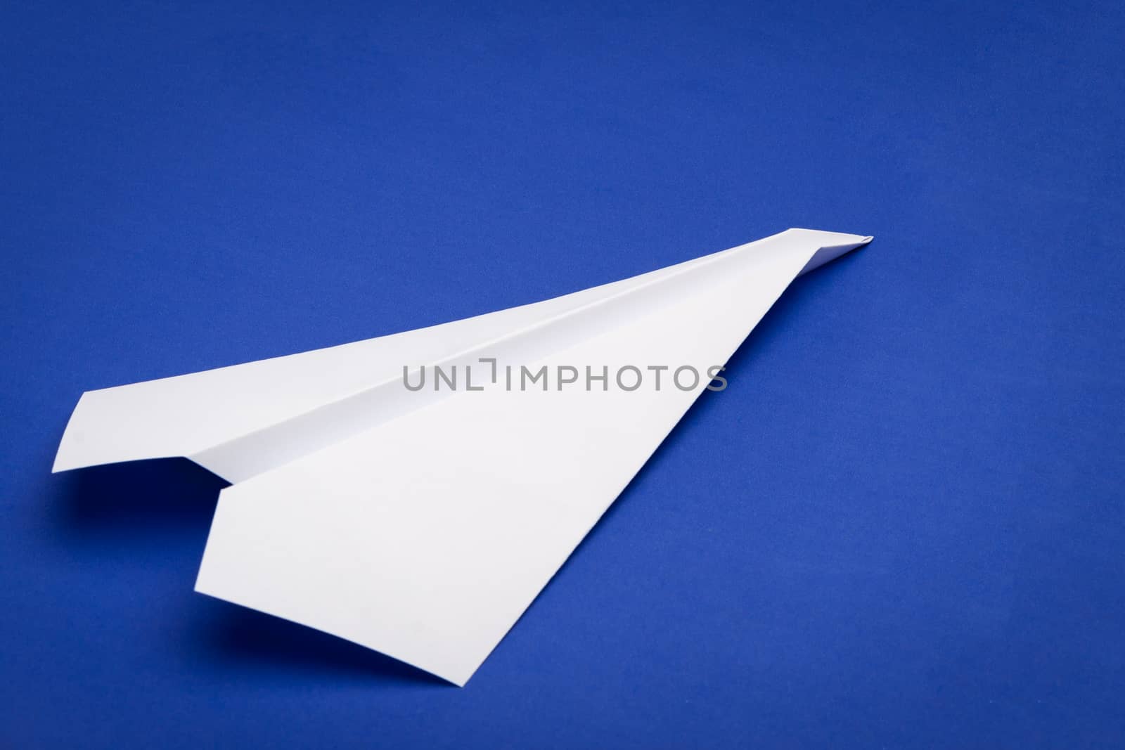 white paper plane on blue paper background