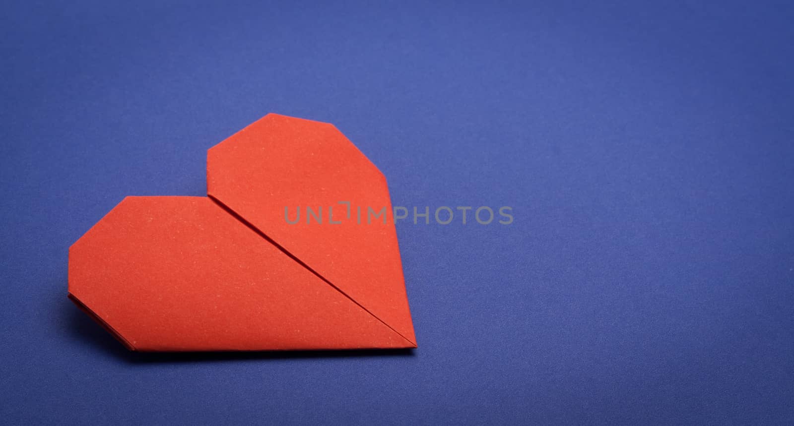 red origami paper heart on blue paper background