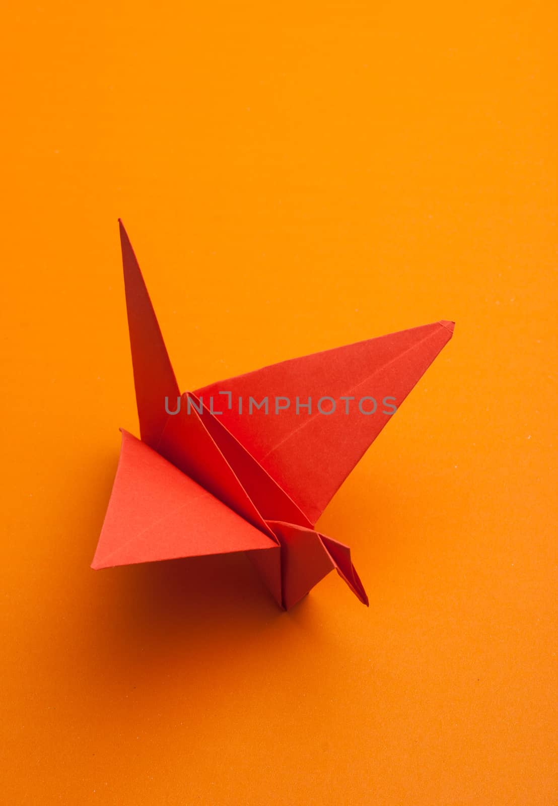 red origami paper crane on orange paper background