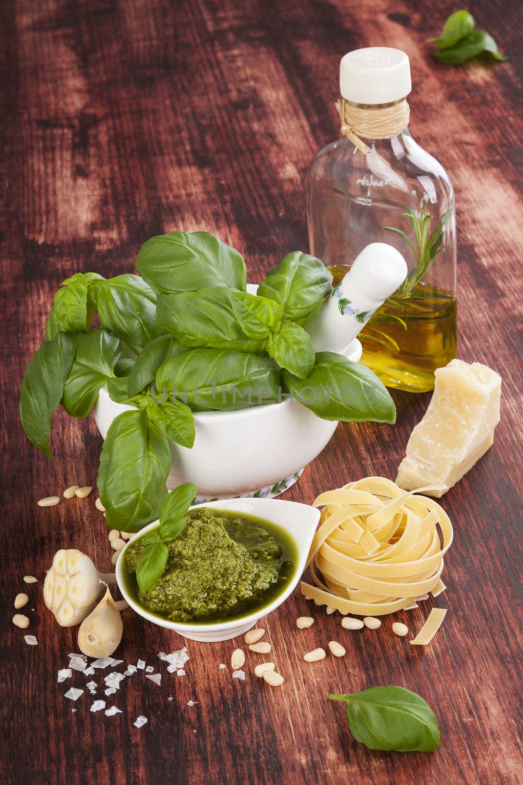 Basil pesto, fresh basil herbs, pasta, olive oil and garlic on wooden background. Italian and mediterranean cuisine ingredients. Healthy culinary eating.