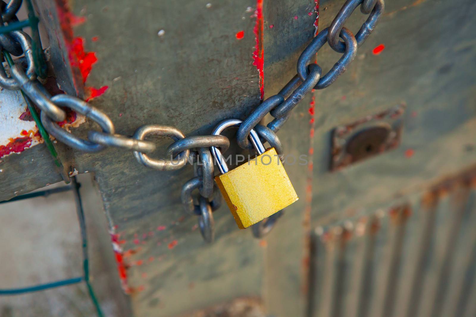 Golden lock closing a big chain over a fence