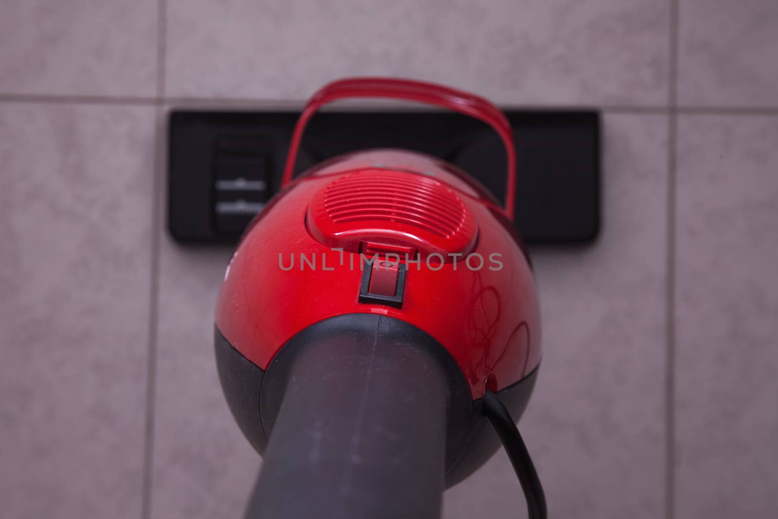 Red vacuum cleaner working over floor, seen from above