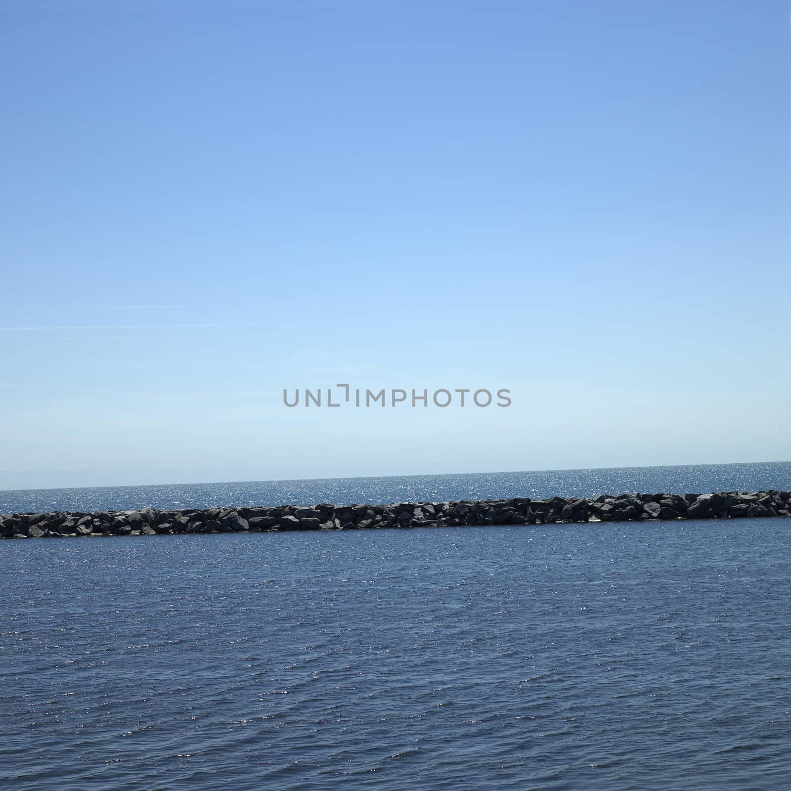 Large stone wall on a blue lake