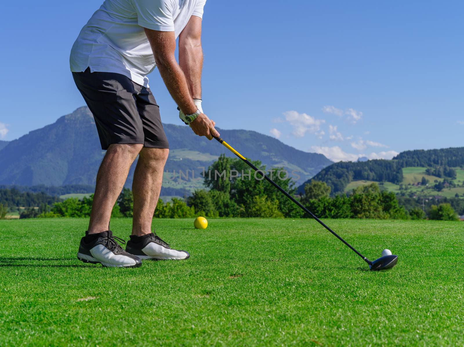 Photo of a male golfer about to tee off on the golf course.