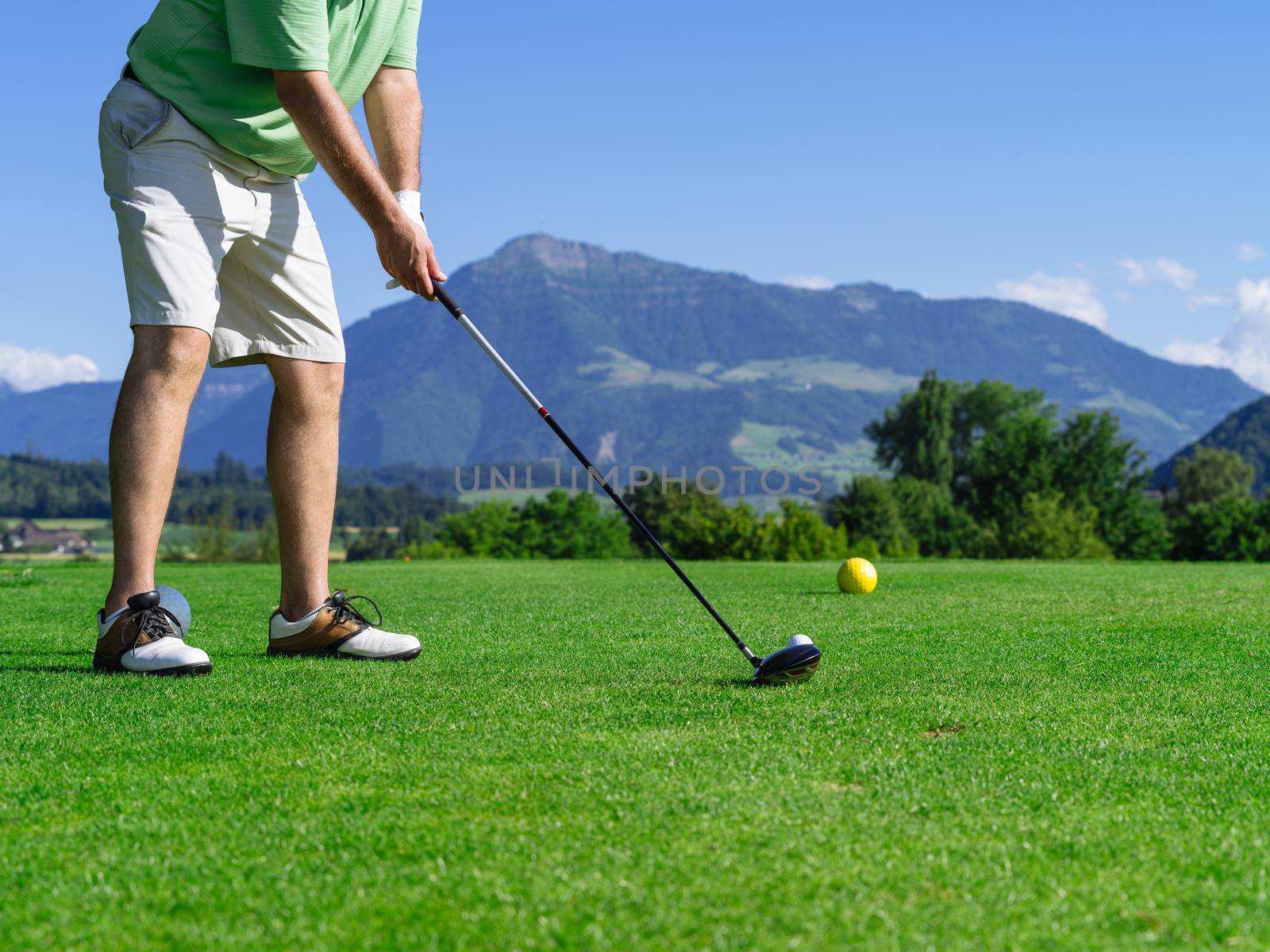 Photo of a male golfer about to tee off on the golf course.
