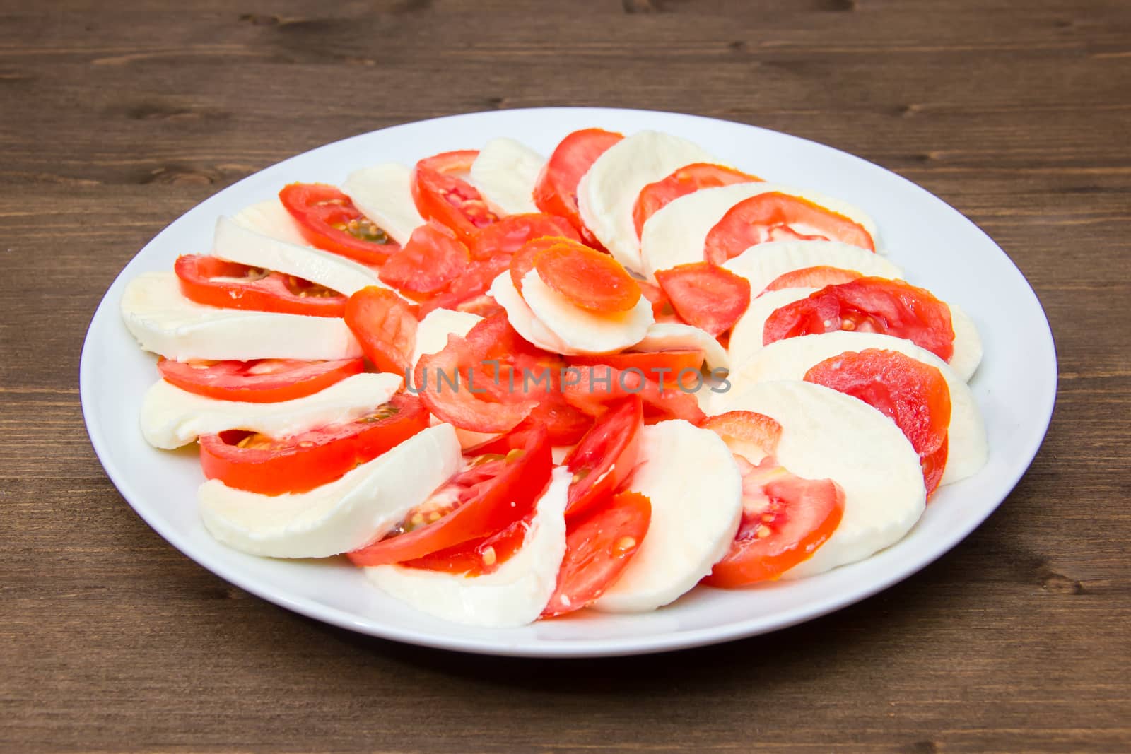 Tomato and mozzarella on a plate on a wooden table