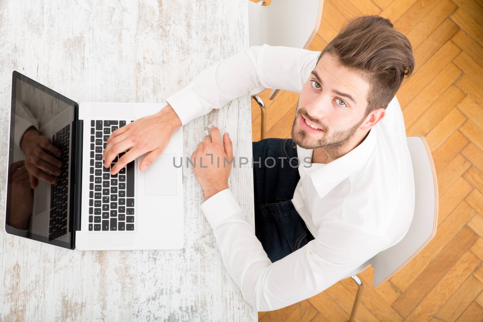A young man sitting at the table with a laptop computer.