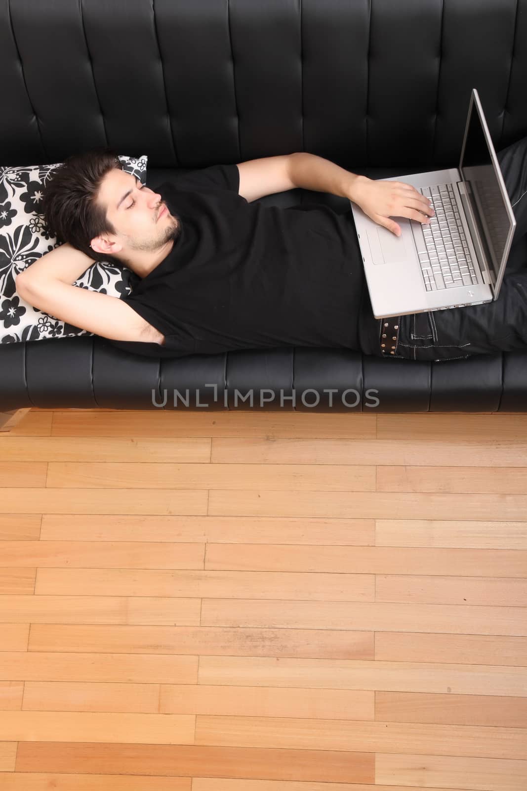 A young hispanic man with a laptop on the Sofa.