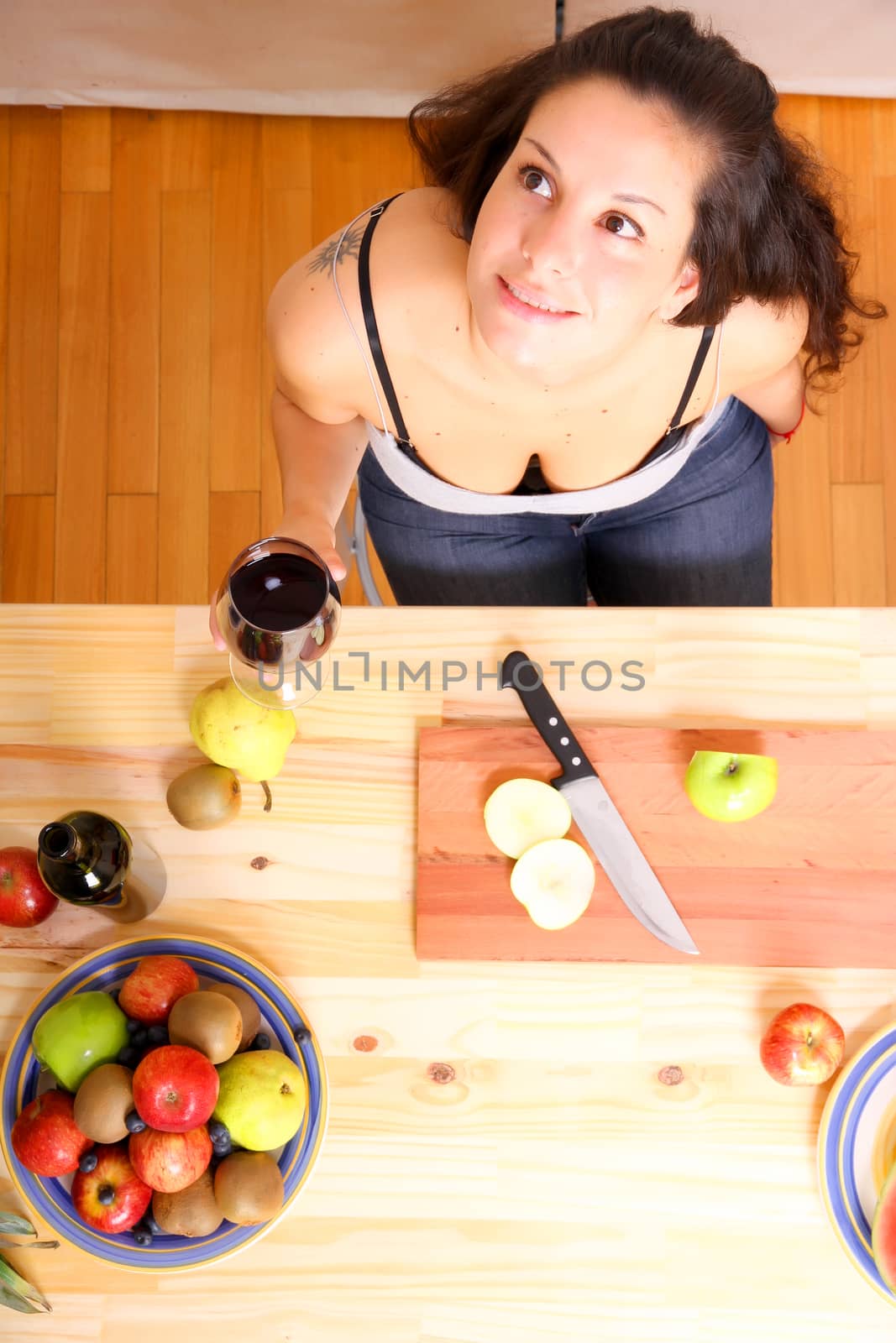 A young adult woman cutting fruits in the kitchen.