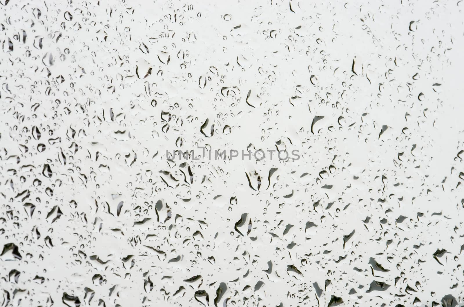 Irregular water drops pattern on glass, close image