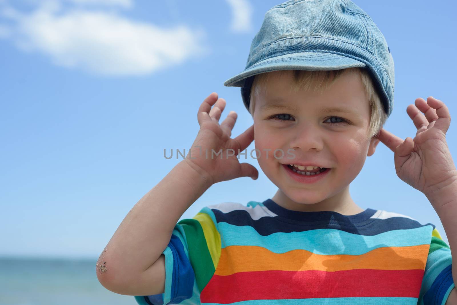 Portrait of small boy holds his hands over ears not to hear