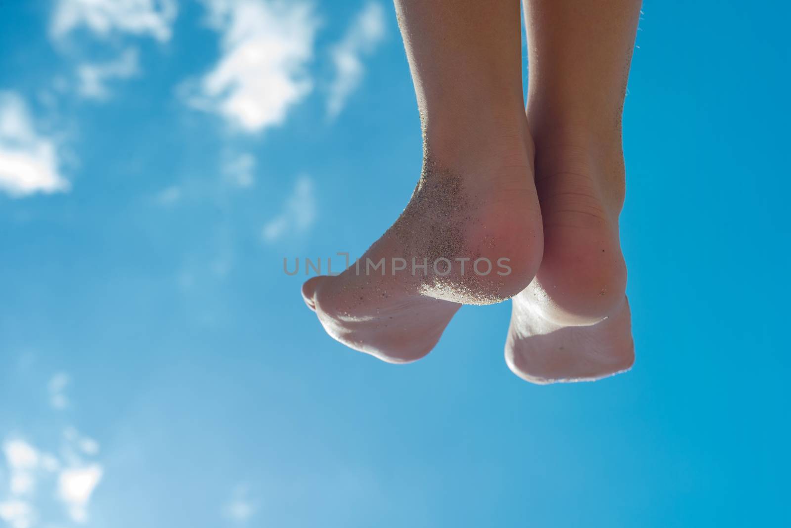 Children's feet against the blue sky with clouds