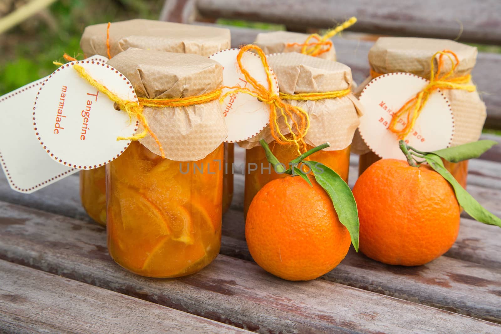 Homemade tangerine marmalade and fresh tangerines on the wooden surface