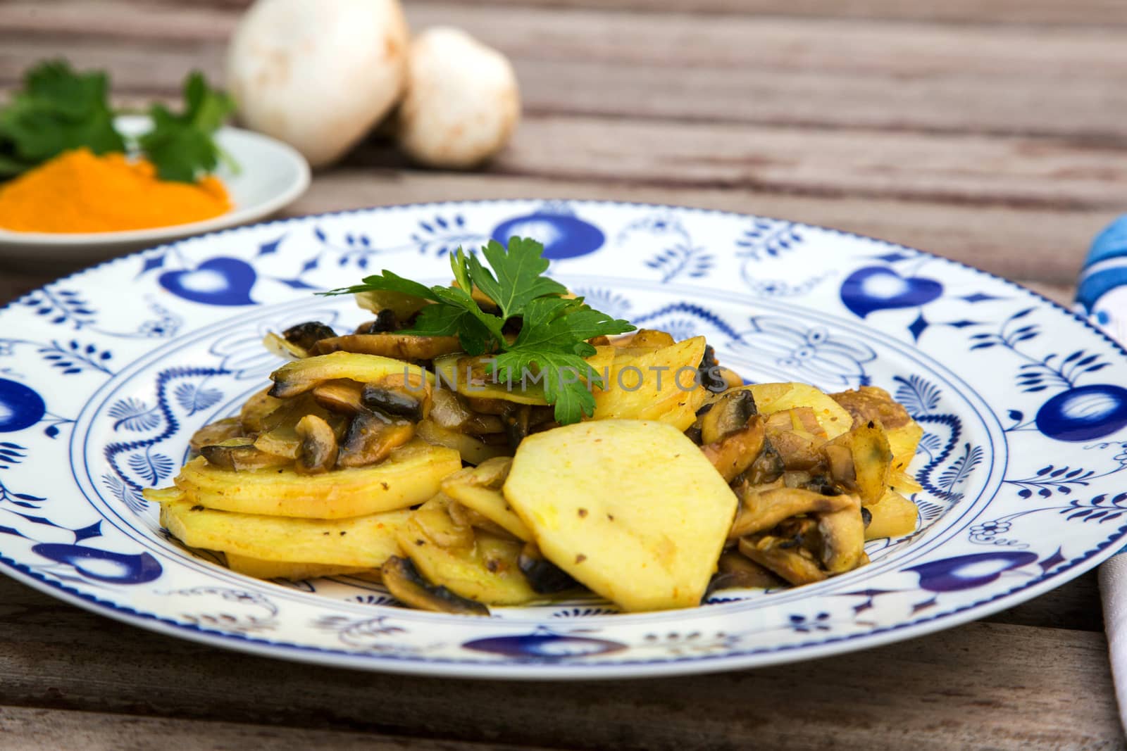 Baked potatoes with mushrooms and curcuma. Decorated by fresh parsley.Ingredients in the background