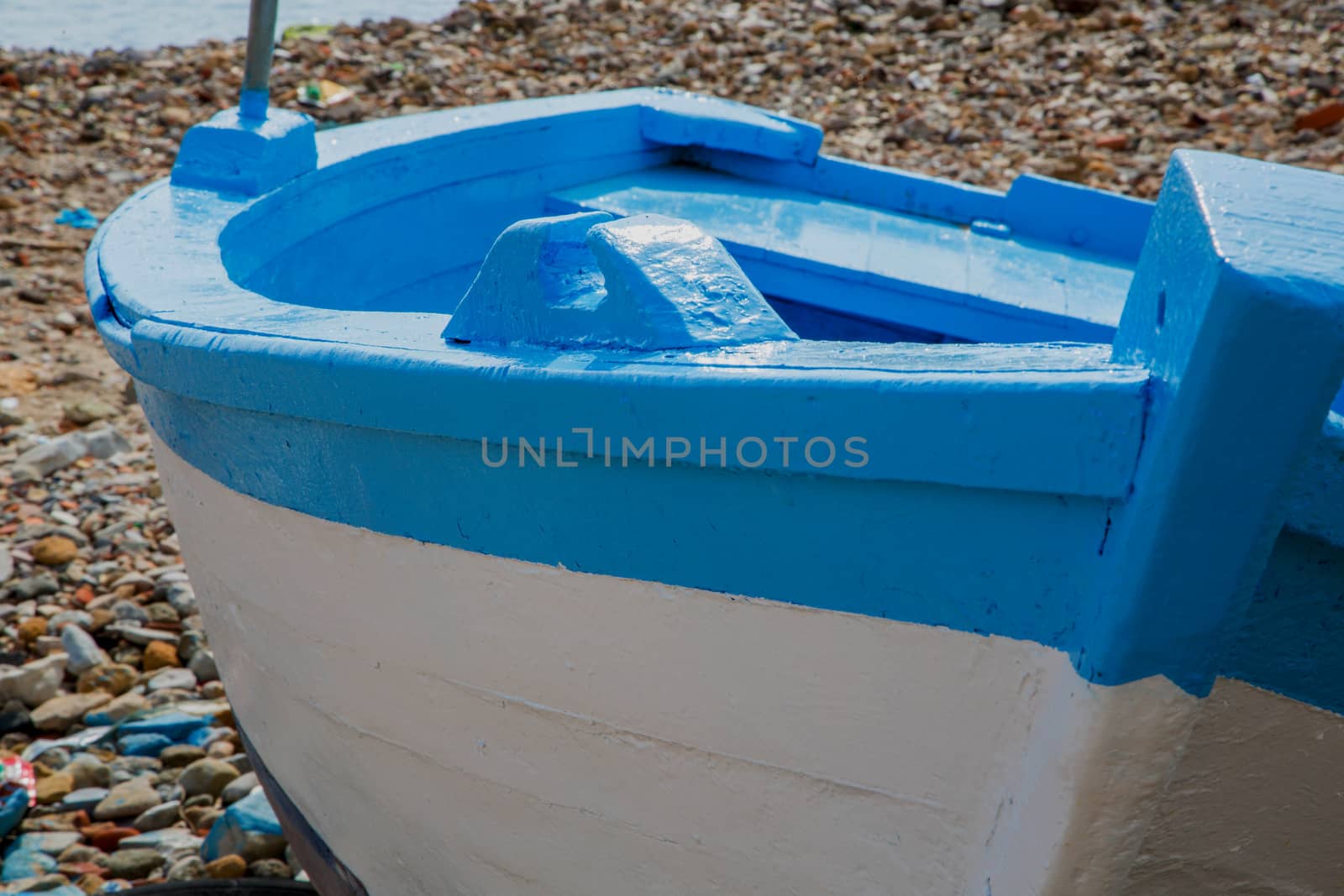 Fresh painted fisherman's boat in white and light blue. Left close to the sea