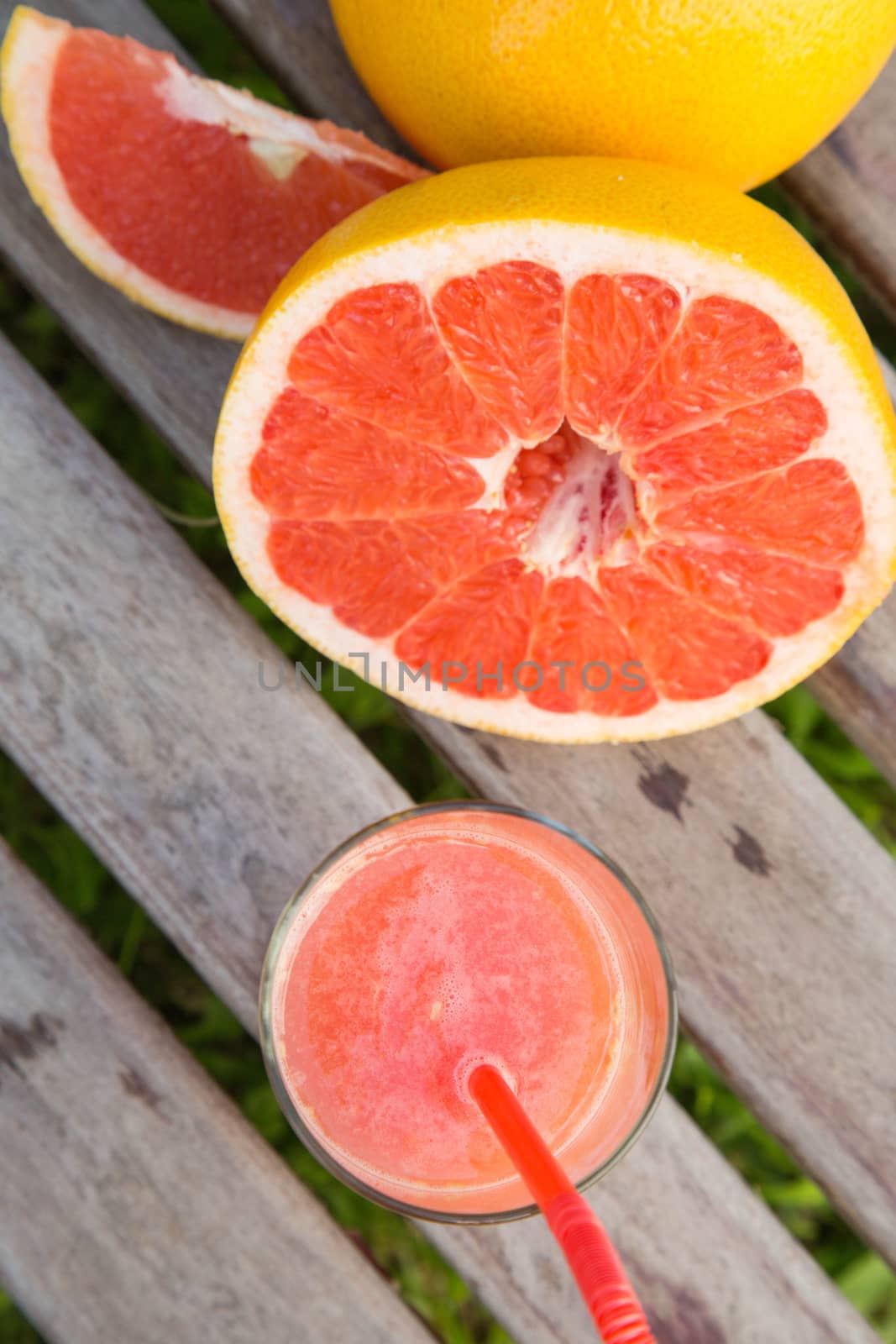 Pieces of grapefruit and a glass of fresh squeezed grapefruit juice on the wooden surface