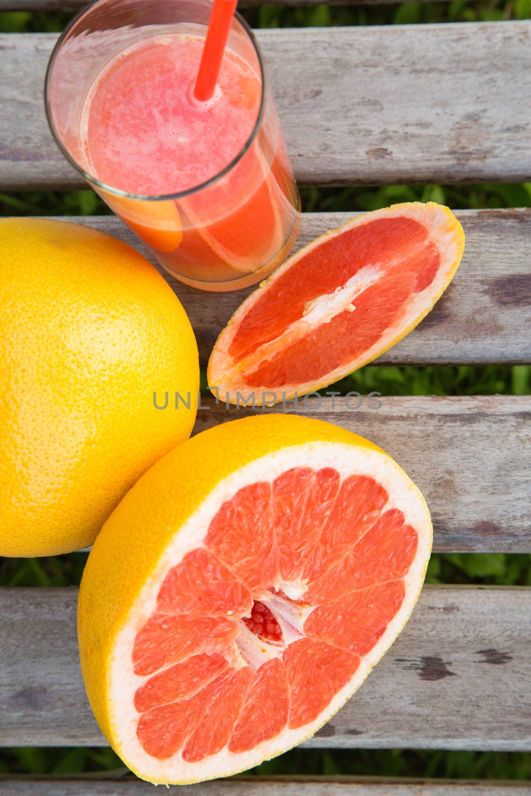 Pieces of grapefruit and a glass of fresh squeezed grapefruit juice on the wooden surface.top view
