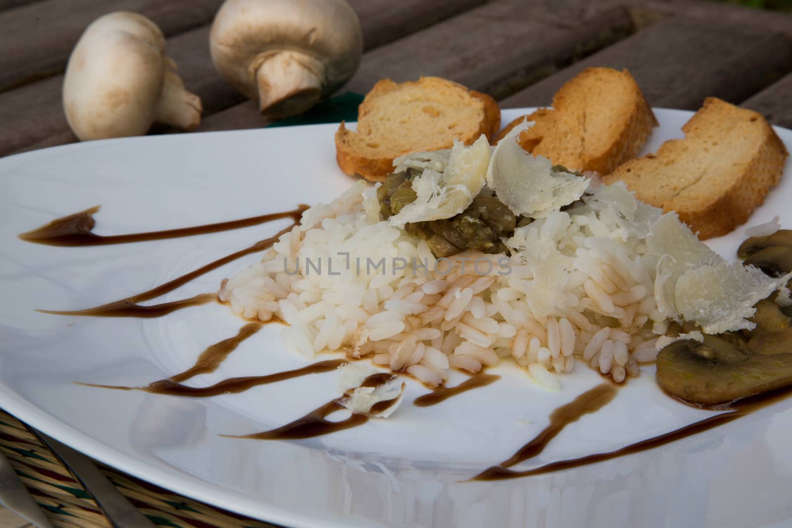 Rice with stewed mushrooms,parmesan and crispy bread on the triangular plate