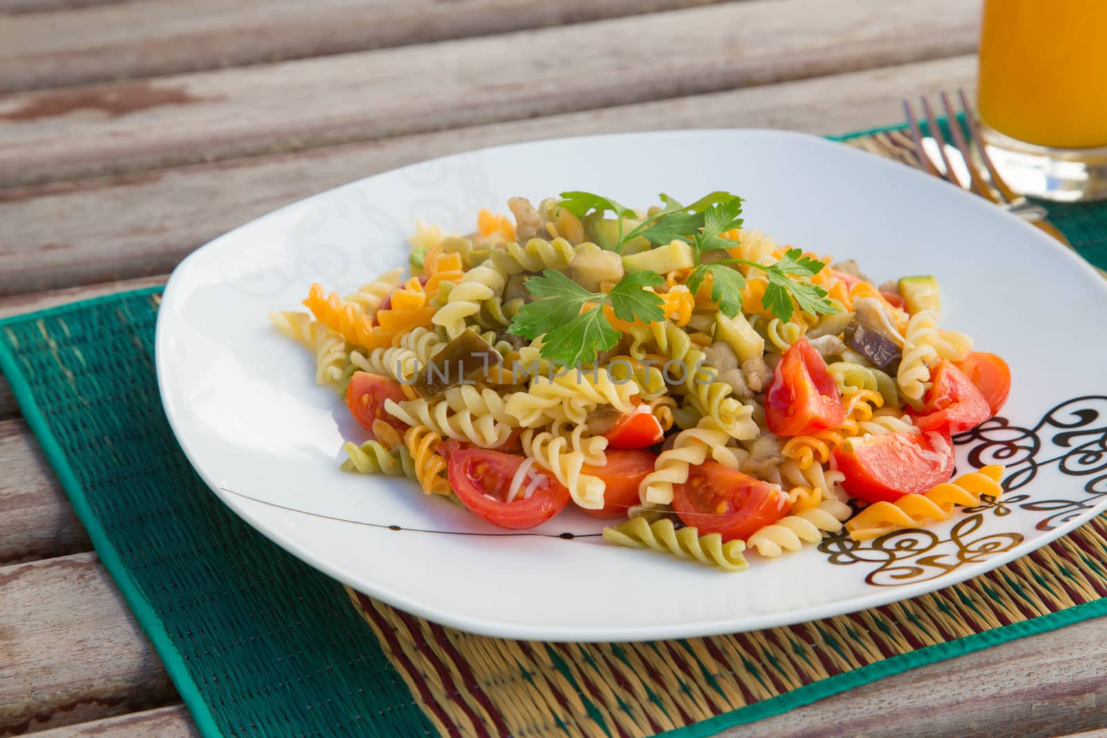 Pasta primavera prepared with three-coloured pasta and vegetables.