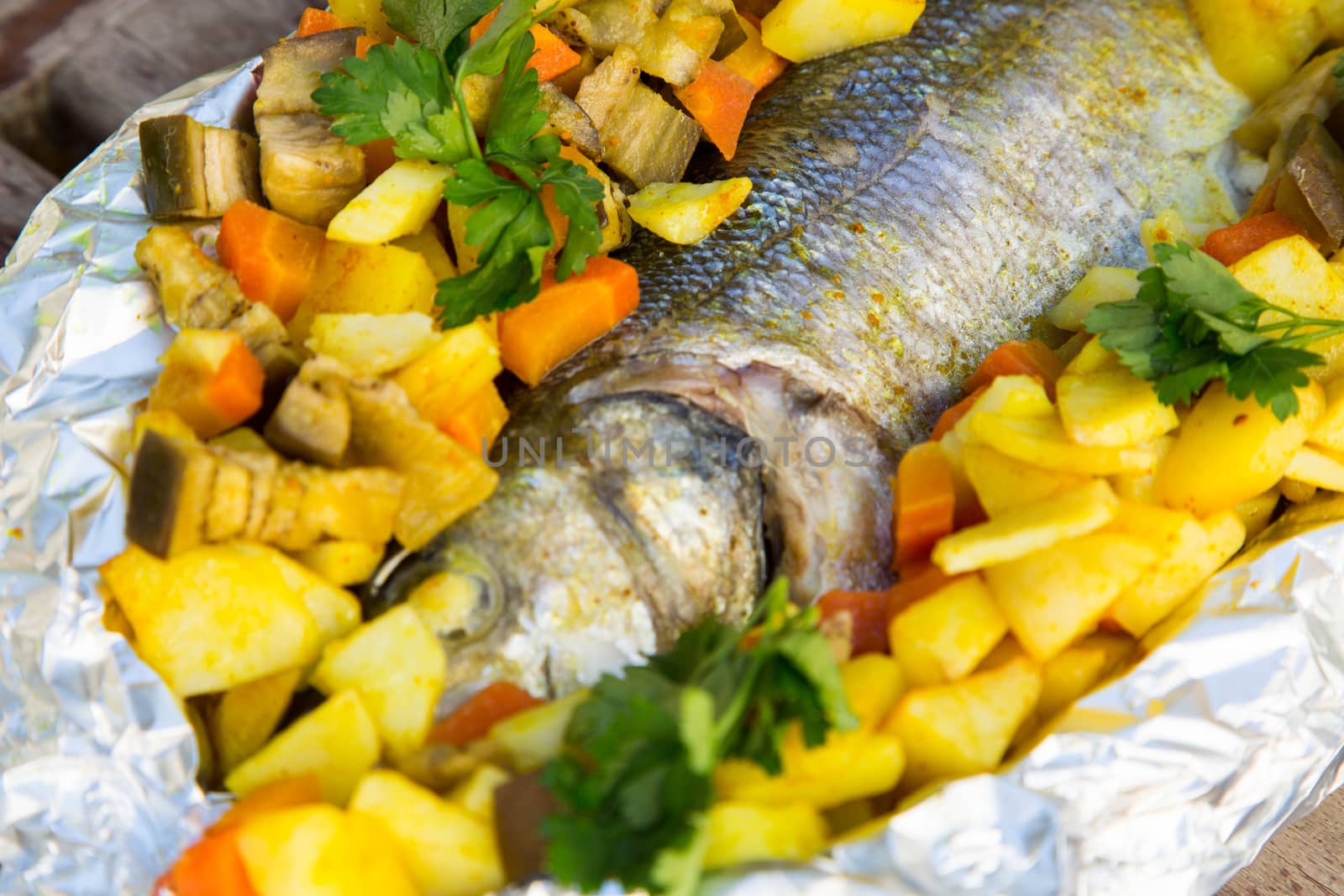 Baked sea bass with vegetables and curcuma in the aluminum foil