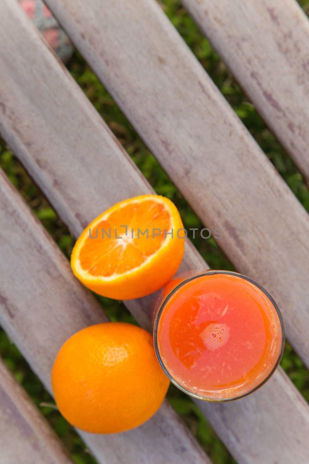 Oranges and a glass of fresh orange juice on the wooden surface.Top view