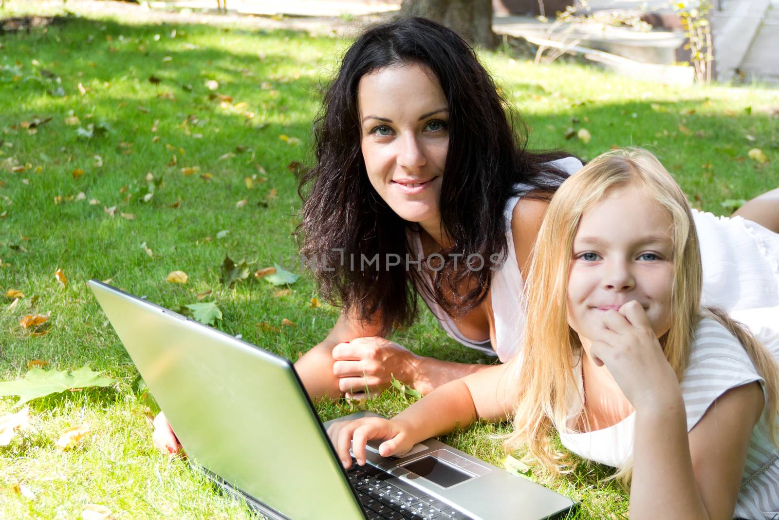 Smiling mother and daughter rest upon herb in summer