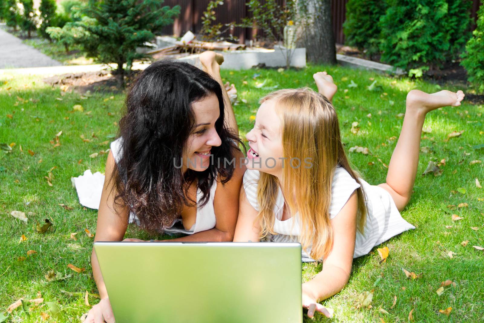 Smiling mother and daughter rest upon herb in summer