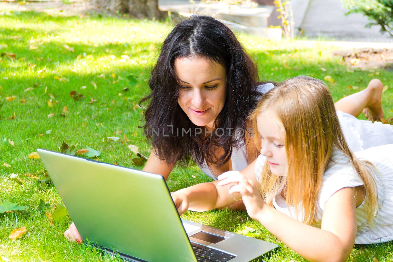 Smiling mother and daughter rest upon herb in summer