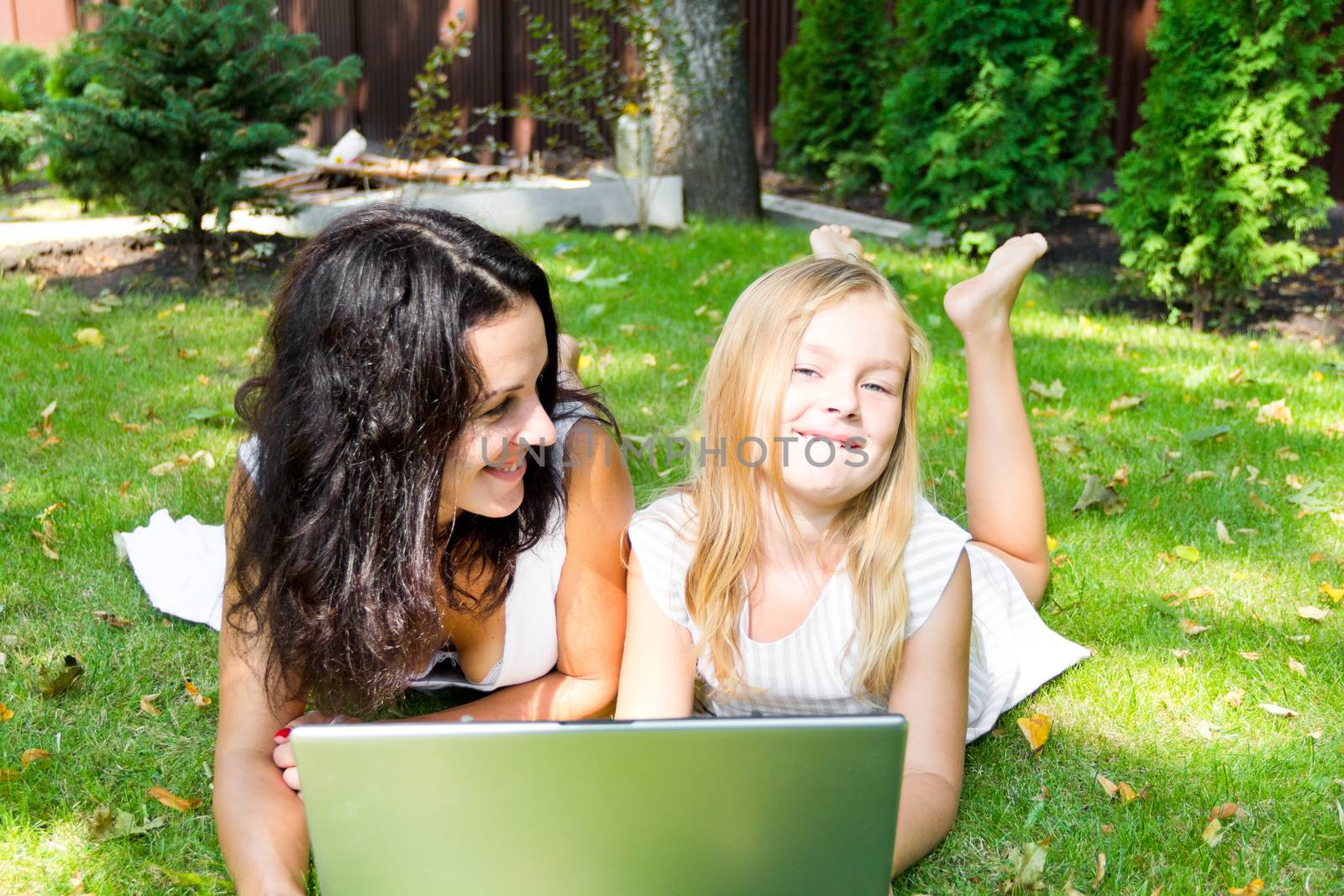 Smiling mother and daughter rest upon herb in summer