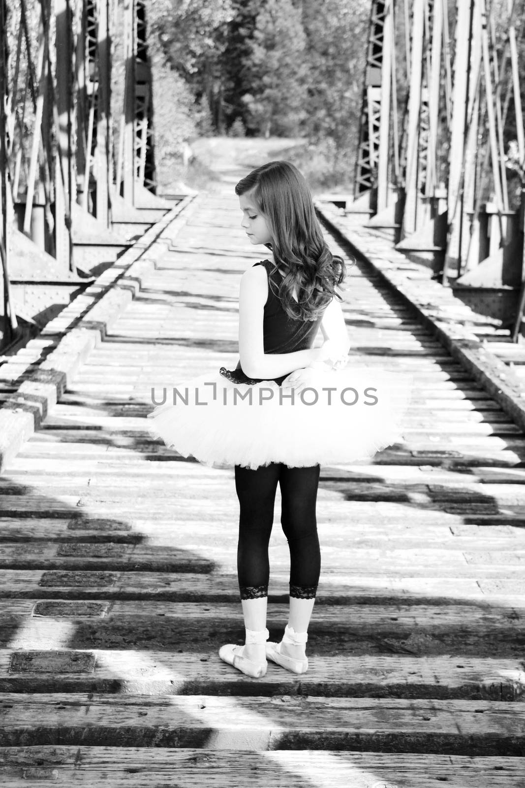 Beautiful girl wearing a white tutu standing on a bridge 