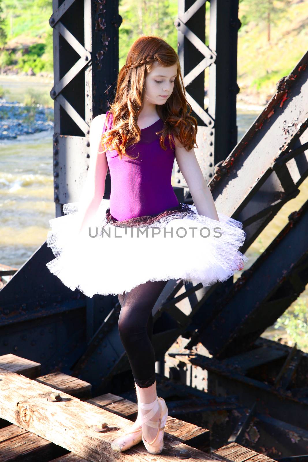 Beautiful girl wearing a white tutu standing on a bridge 