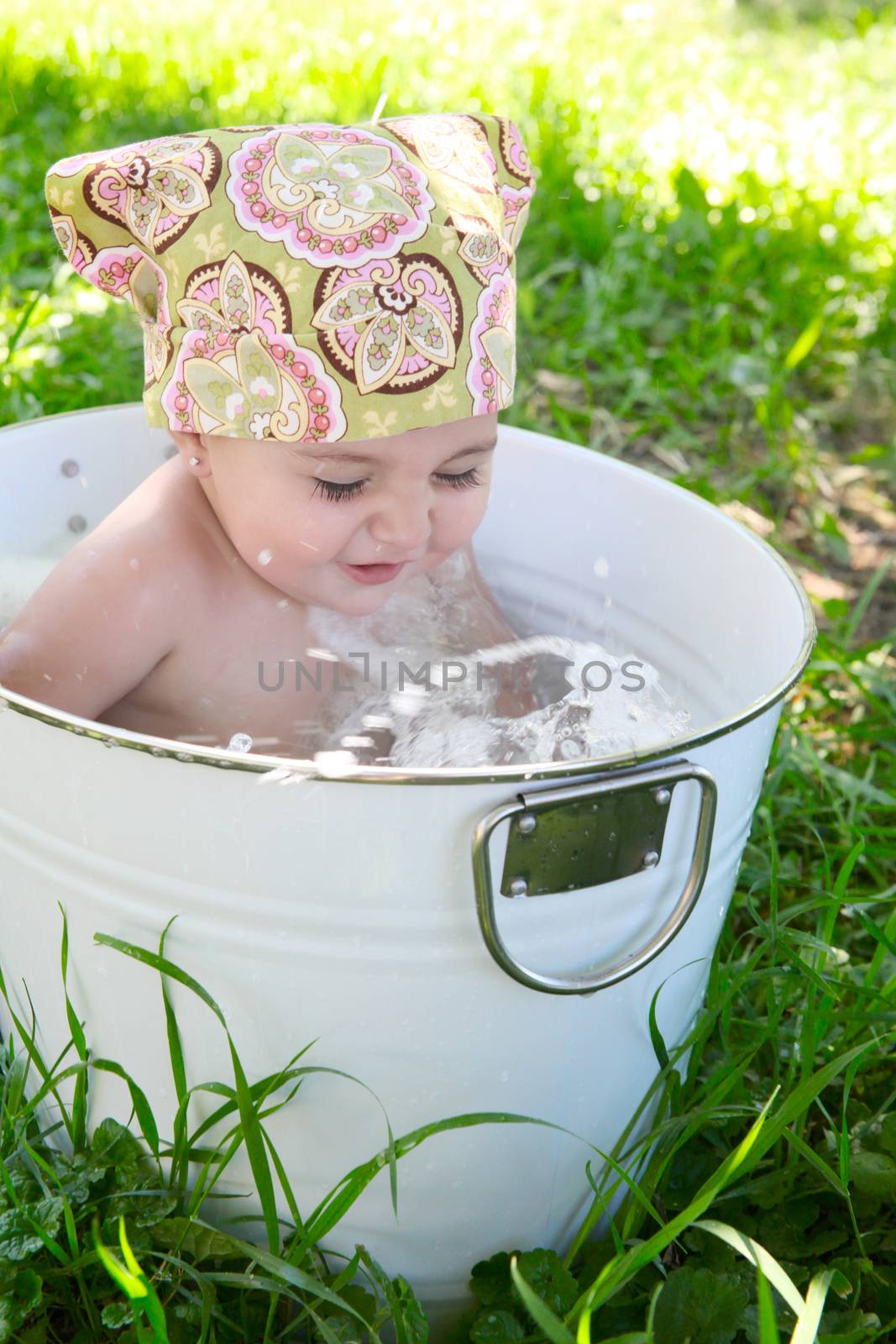 Beautiful baby girl having a bath outdoors