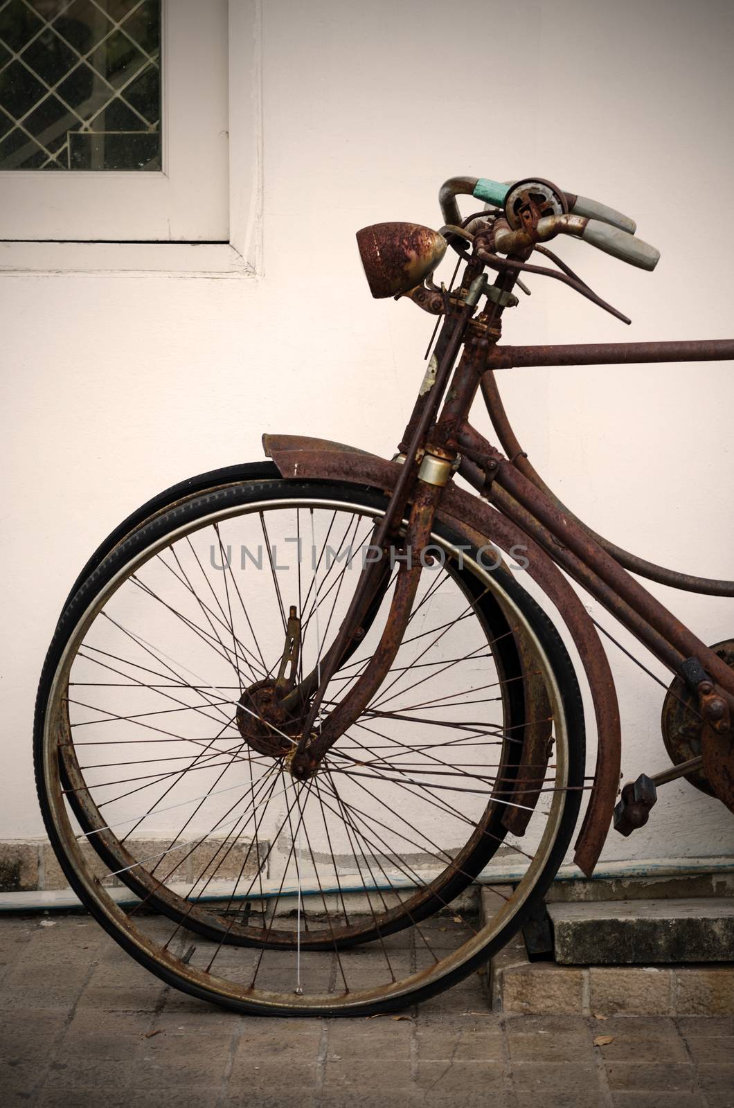 Old rusty bicycle near concrete wall, sepia filter by siraanamwong