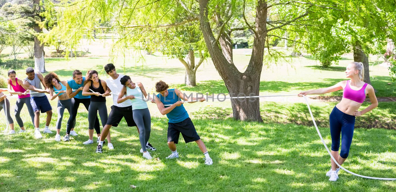 Fit woman playing tug of war with group of friends in the park