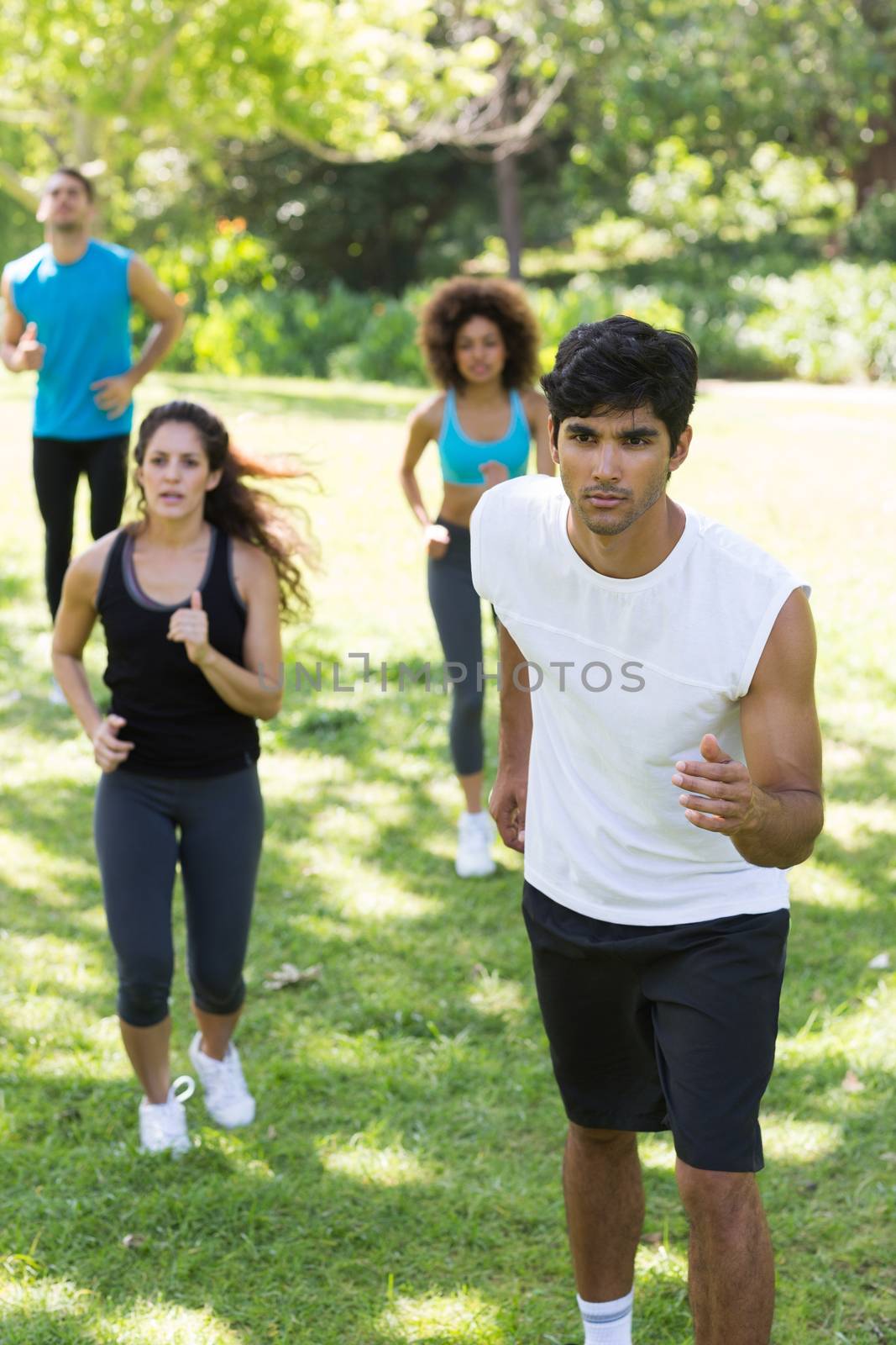 Group of athletes jogging on grassy land in park